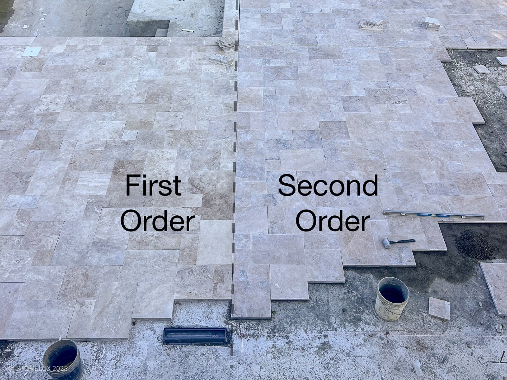 A pool deck installation showing a visible color difference between two sections of travertine pavers. The left side, labeled “First Order,” has a darker, more varied silver-beige tone, while the right side, labeled “Second Order,” appears noticeably lighter and more uniform. Tools, buckets, and construction materials are visible around the work area, illustrating a mismatch between stone lots used in separate orders.