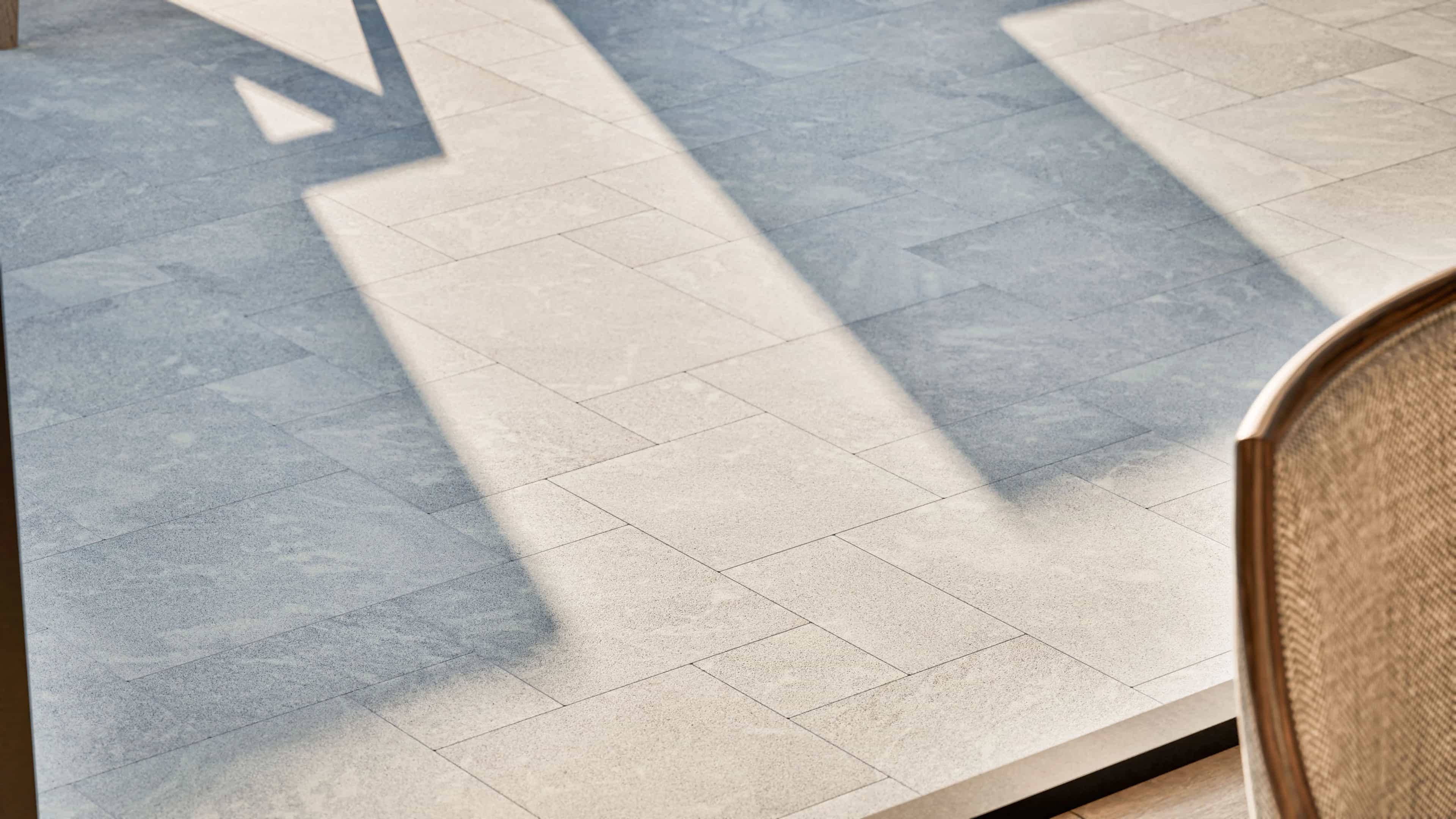 Design visualization of Afyon Grey Marble French Pattern pavers around a modern pool and patio, showing the collection's light cool-grey tone, fine blue-grey speckling, and soft cloudy movement.
