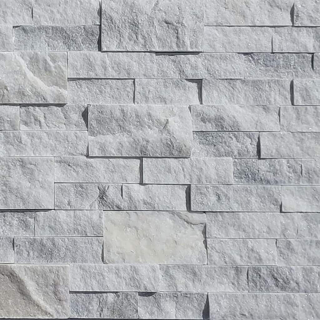 Close-up of Afyon White Marble Splitface Ledger Panel in 6x24 size. The natural stone features a textured splitface finish with subtle gray veining and a creamy white tone, ideal for elegant wall cladding in modern and traditional designs.