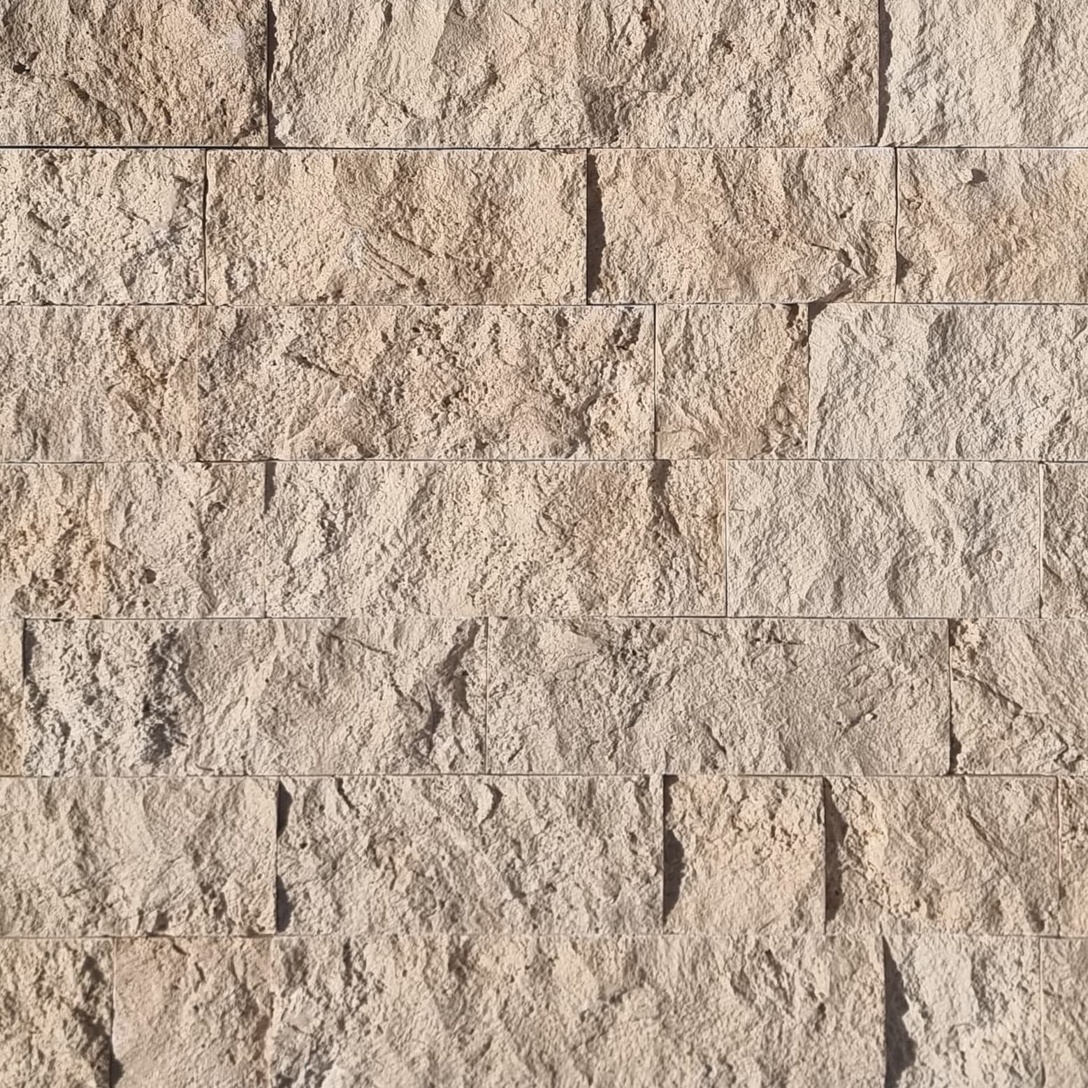 Close-up of Ivory Travertine Splitface Veneer showcasing its textured surface and natural beige tones. The 4" x Free Length travertine features subtle veining, ideal for adding rustic elegance to facades and accent walls. Perfect for stone veneer proje...