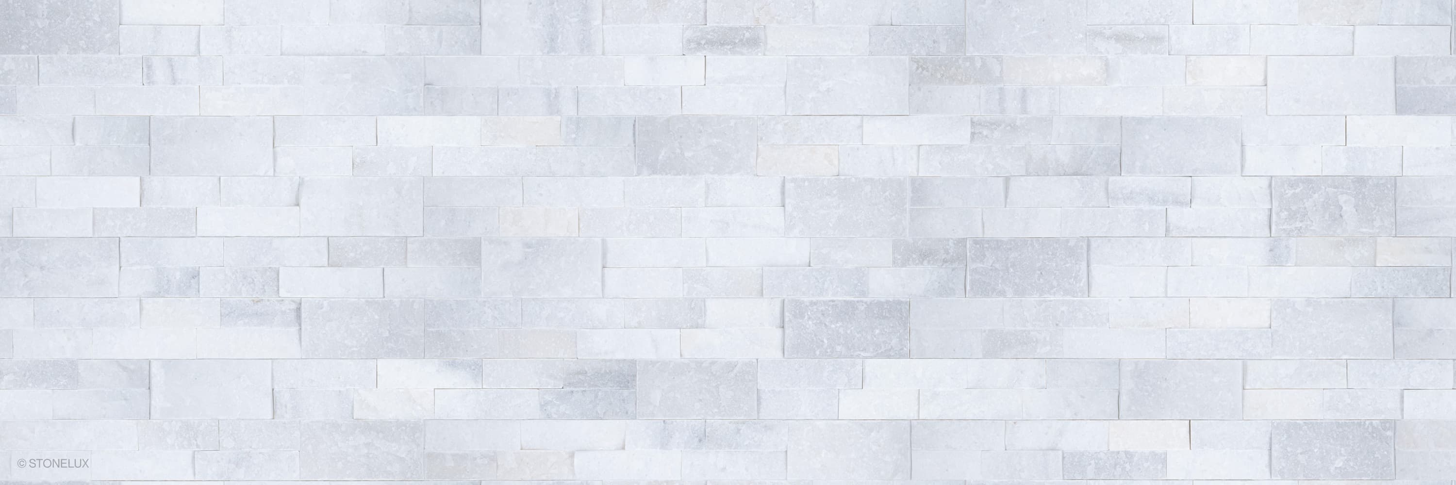 Afyon White Marble Splitface Ledger Panel 6x24 showcases a textured, natural stone surface with subtle white and gray veining. Ideal for wall installations, this veneer panel adds elegance and timeless beauty to interiors and exteriors. Perfect for mod...
