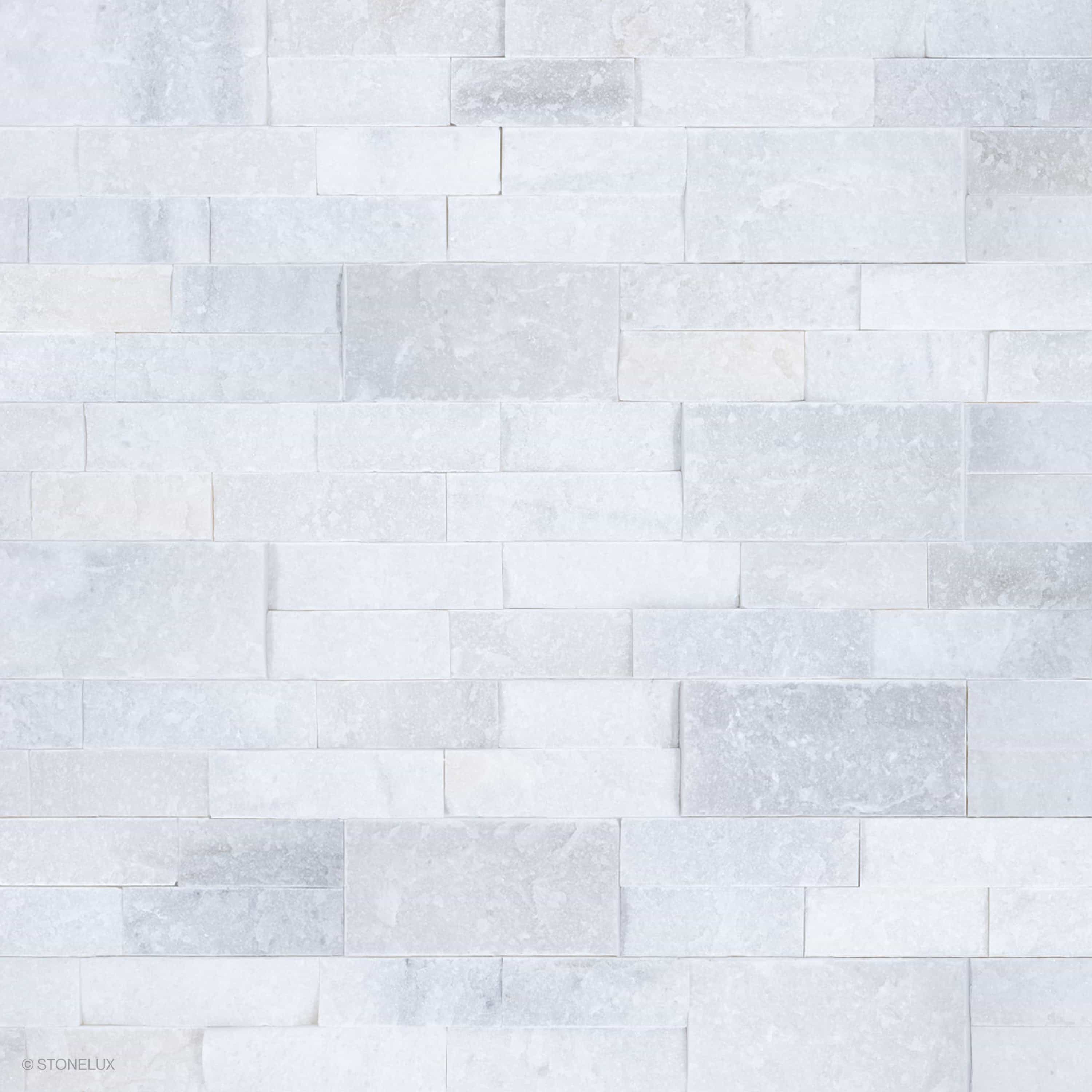 Close-up of Afyon White Marble Splitface Ledger Panel 6x24 by STONELUX, showcasing its textured splitface finish and elegant white and gray veining. Ideal for veneer wall projects, offering a timeless and luxurious aesthetic for interior and exterior d...