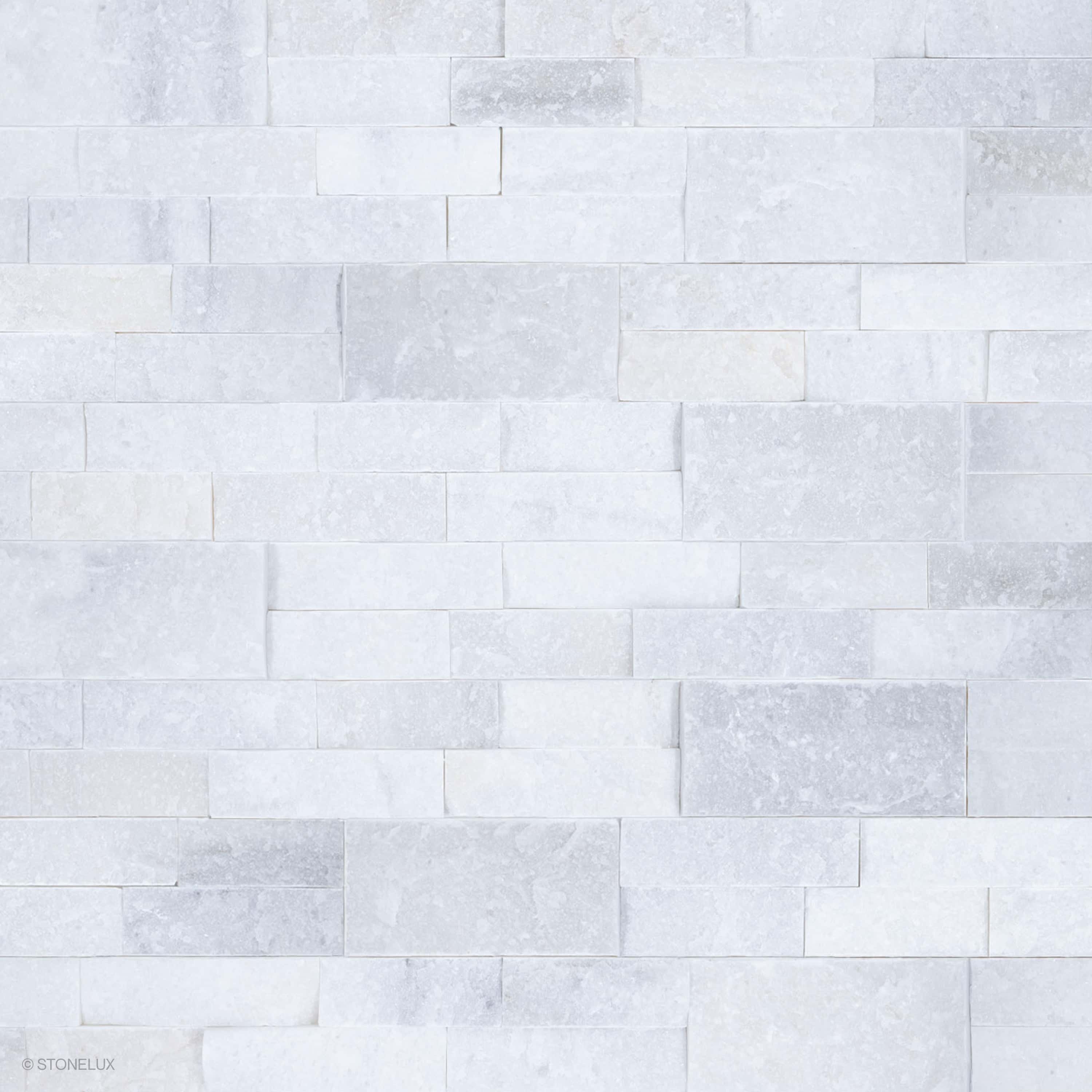 Close-up of Afyon White Marble Splitface Ledger Panel 6x24 by STONELUX, showcasing its textured splitface finish and elegant white and gray veining. Ideal for veneer wall projects, offering a timeless and luxurious aesthetic for interior and exterior d...