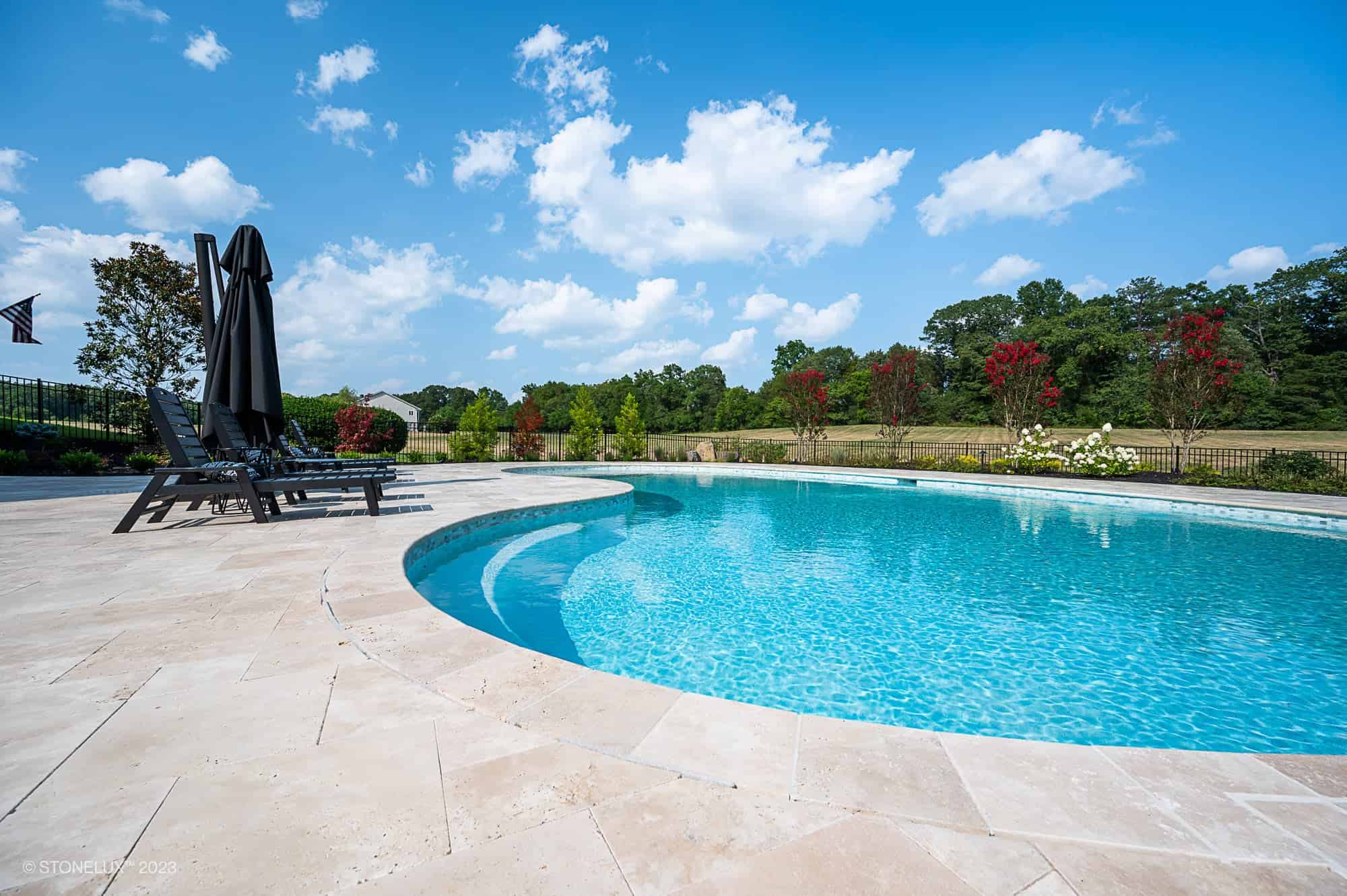 Ivory Travertine pool coping and tumbled travertine pavers installed around a residential pool and patio in Nokesville, VA.