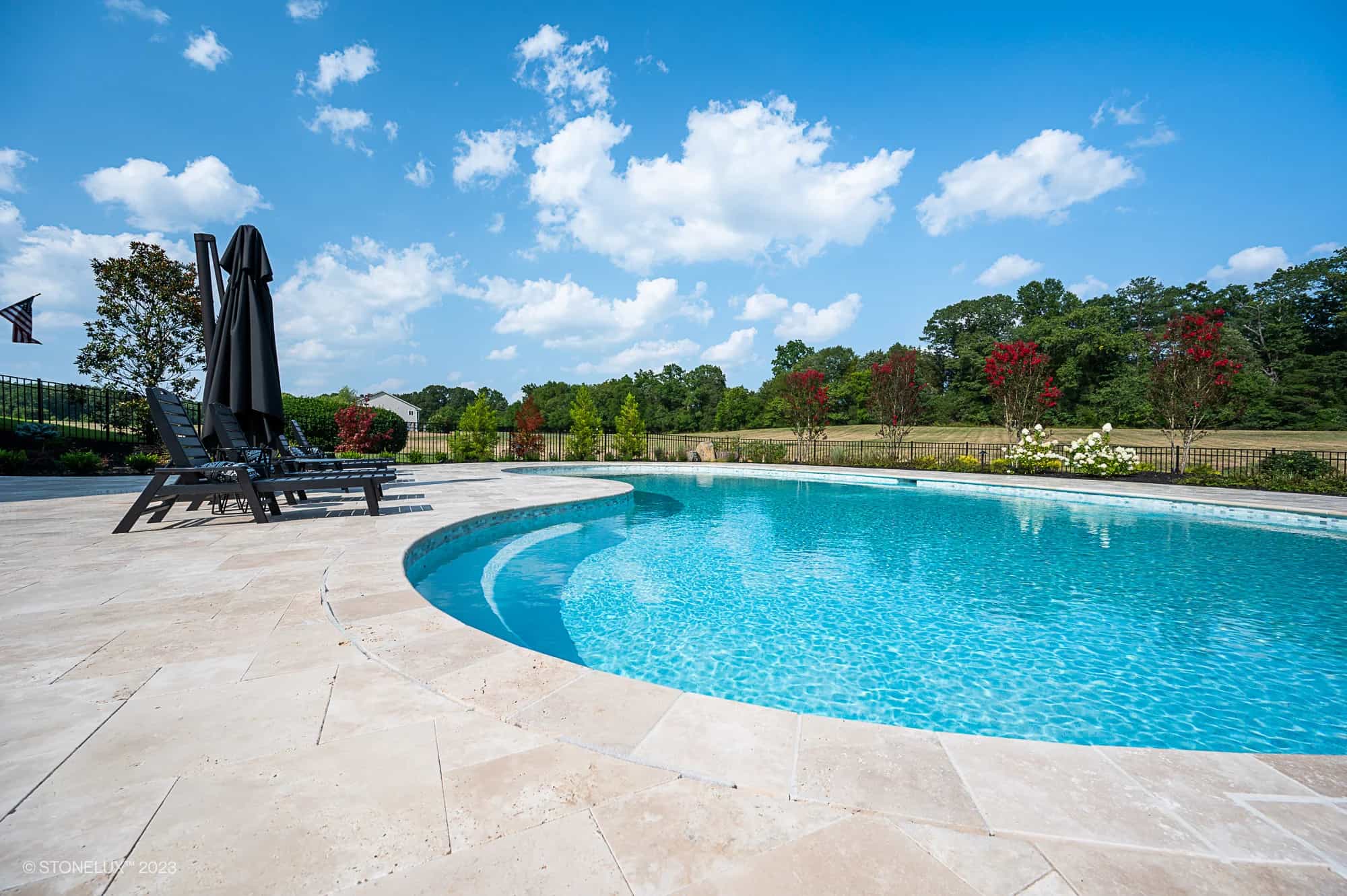 Ivory Travertine pool coping and tumbled travertine pavers installed around a residential pool and patio in Nokesville, VA.