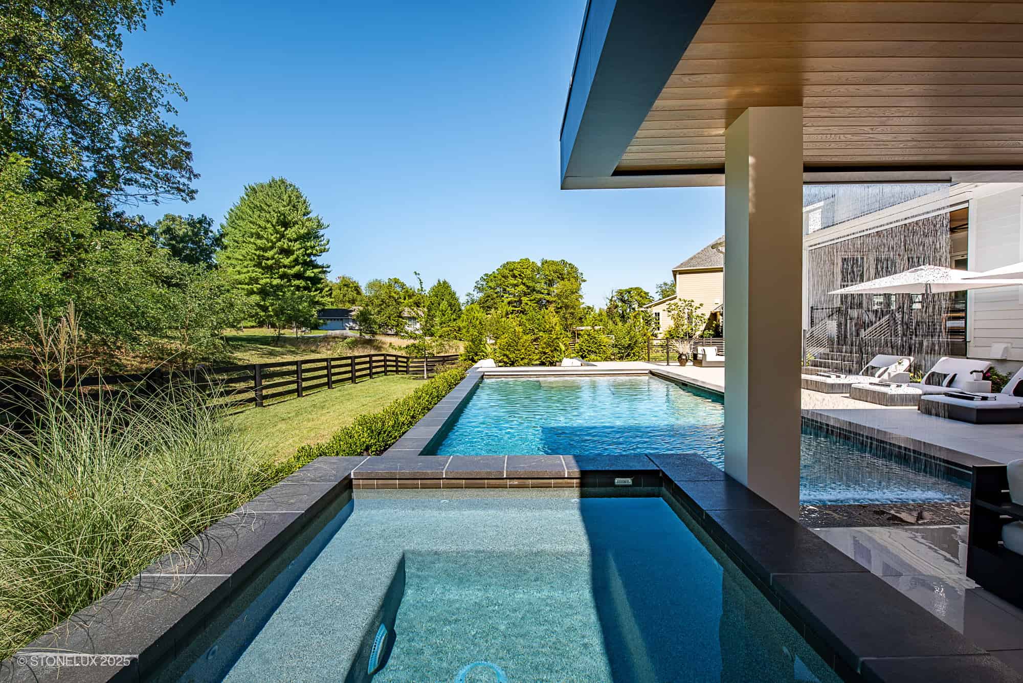 Modern pool and spa with Black Basalt eased edge coping and porcelain pavers in Aldie, VA.