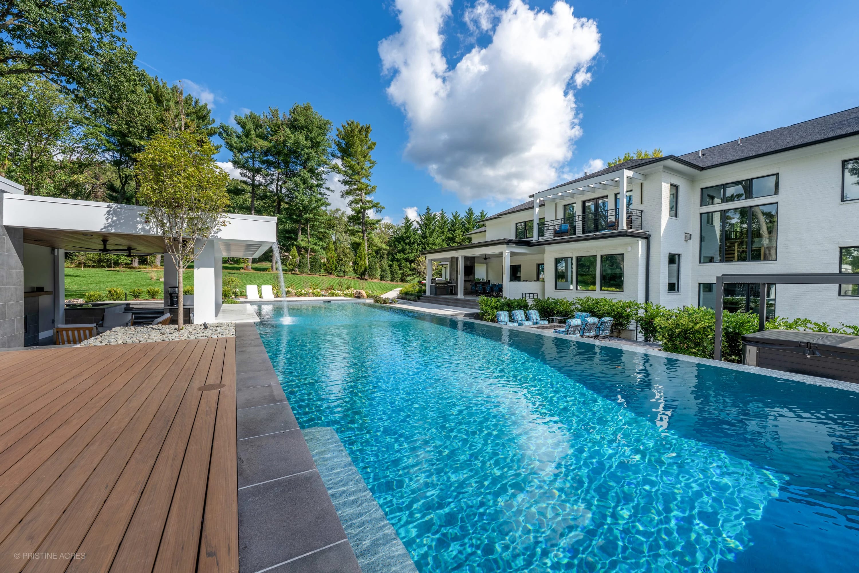 Modern McLean Pool Project in McLean VA features a sleek design with Black Basalt coping and Nexus White Porcelain pavers. The crystal-blue pool complements modern architecture, lush greenery, and stylish outdoor seating, creating a luxurious backyard ...